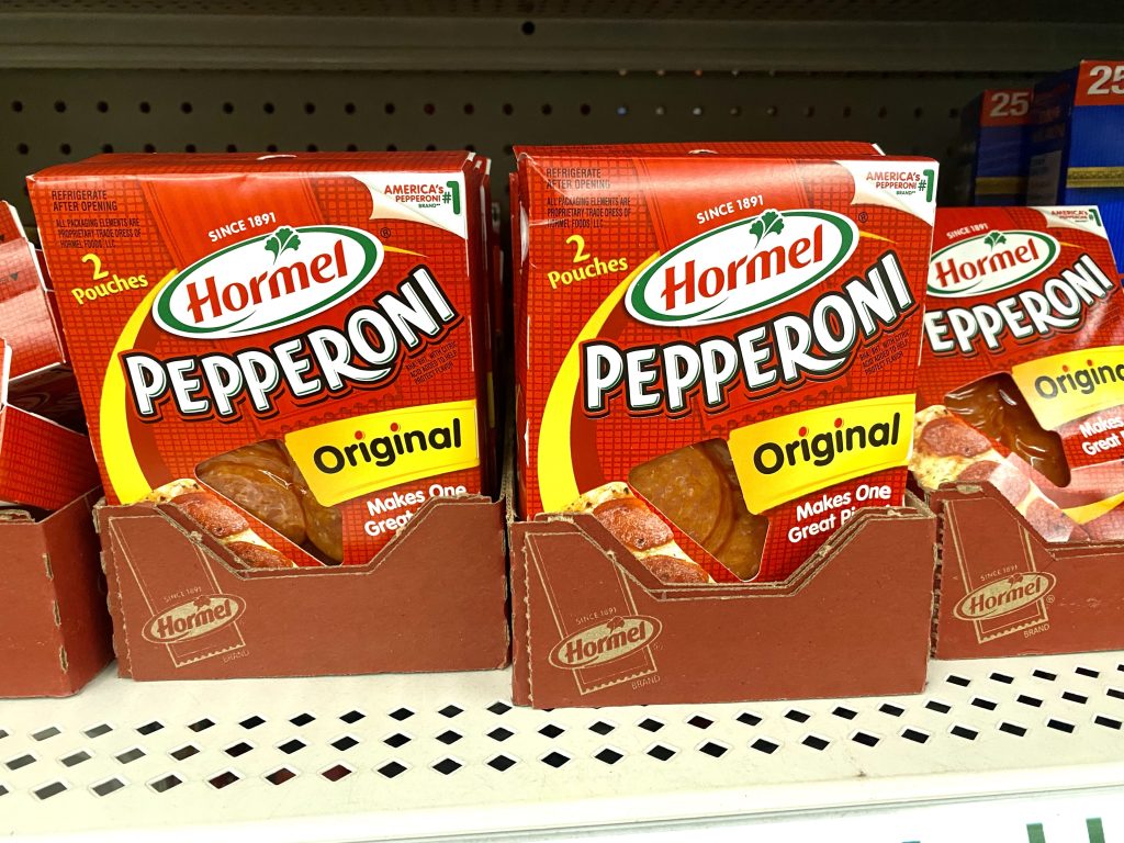 Packages of pepperoni on a store shelf.