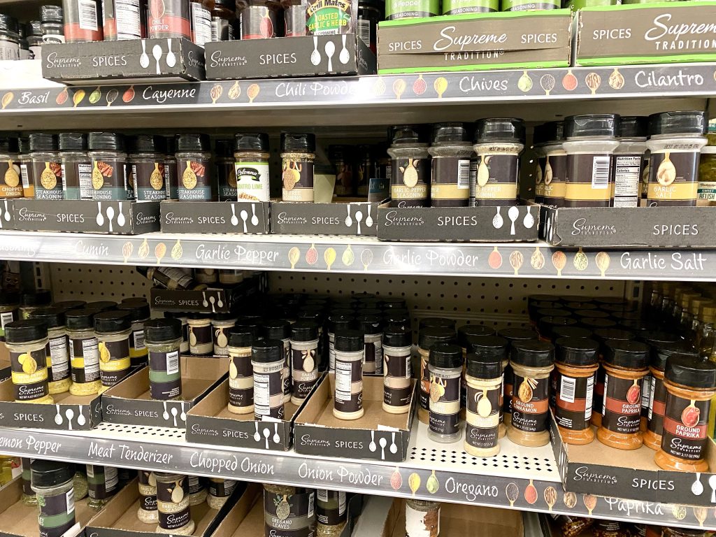 Shelf of many bottles of spices. 