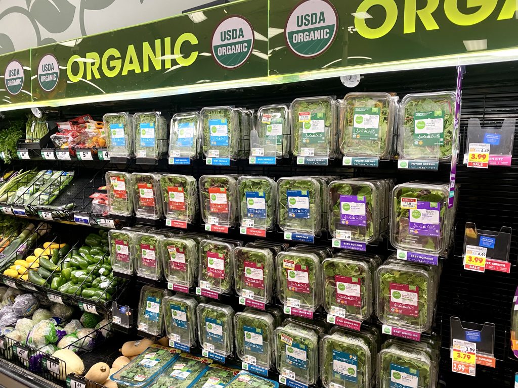 Organic produce section at grocery. a wall of prepackaged greens.