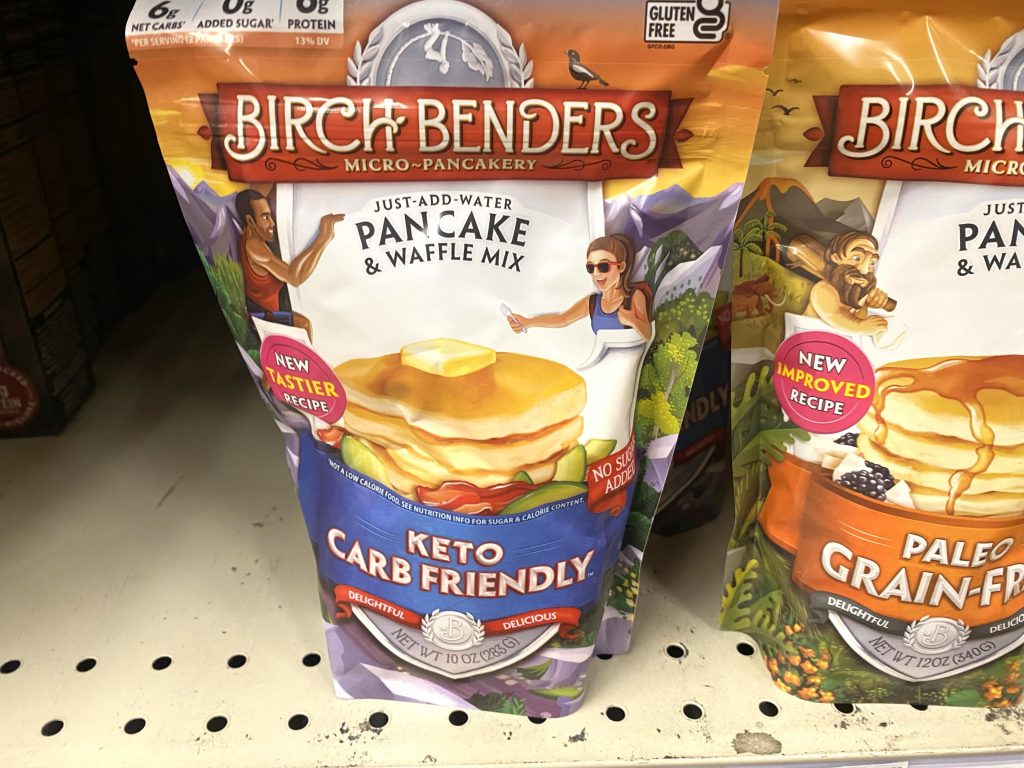 Packages of keto pancake mix on store shelf.