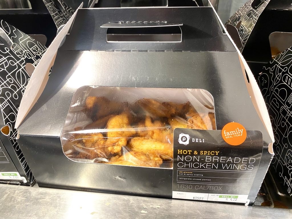 Cooked chicken wings in the heated cabinet of the deli at grocery store.