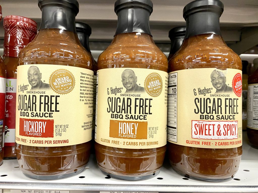 Bottles of sugar free barbeque sauce on shelf at grocery store.