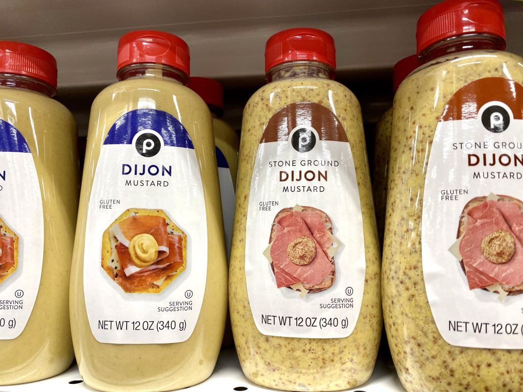 Bottles of Dijon mustard on grocery shelf.