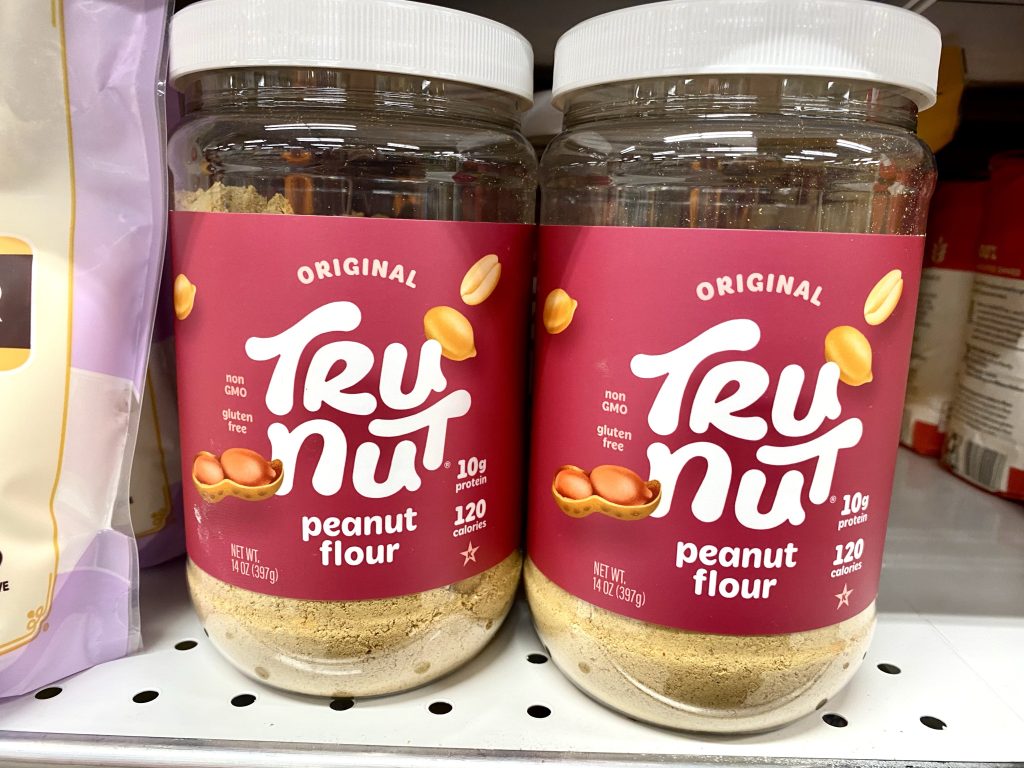 Peanut flour in packages on a store shelf.