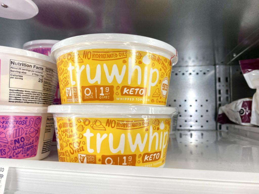 Tubs of keto whipped topping on grocery shelf in freezer section.