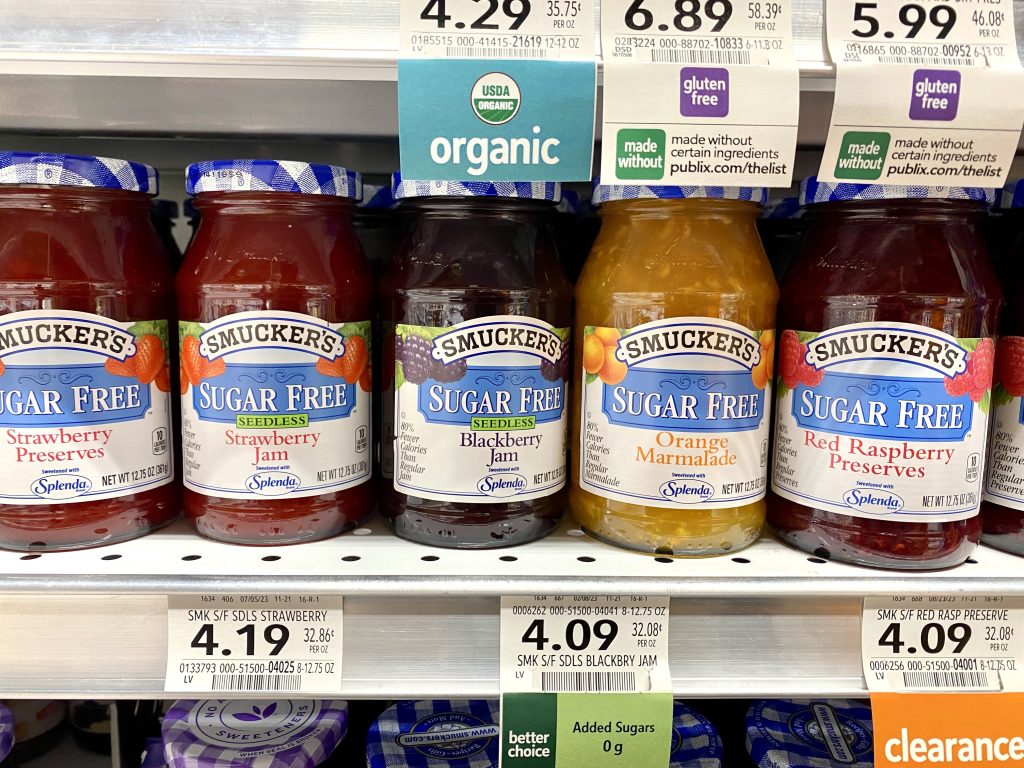 A variety of flavors of sugar free preserves on a grocery shelf.