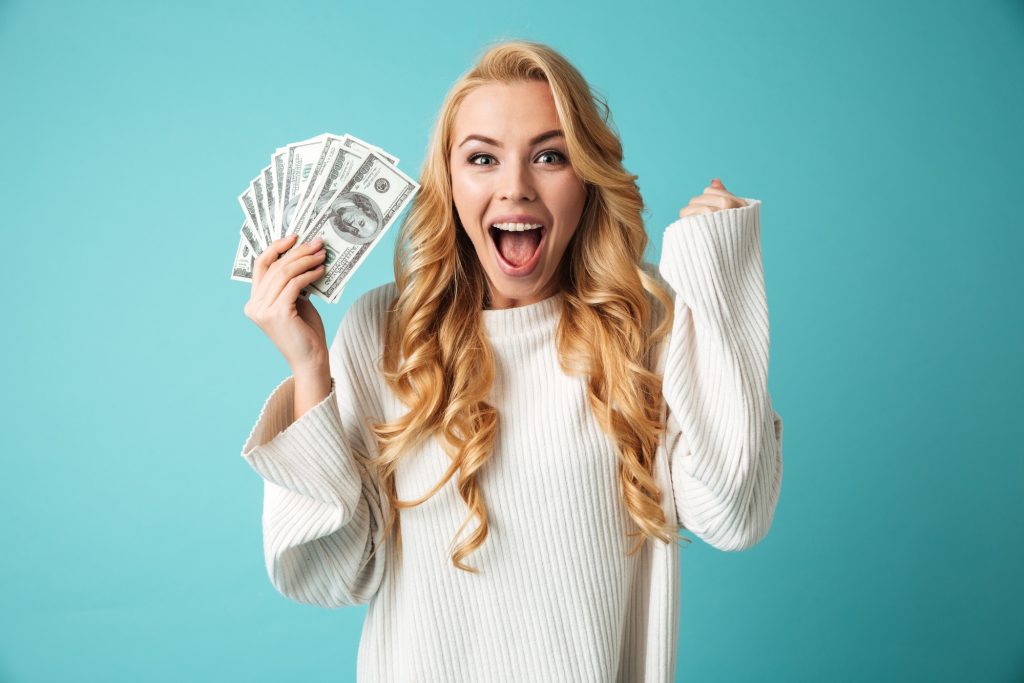 A woman holding cash and looking excited.