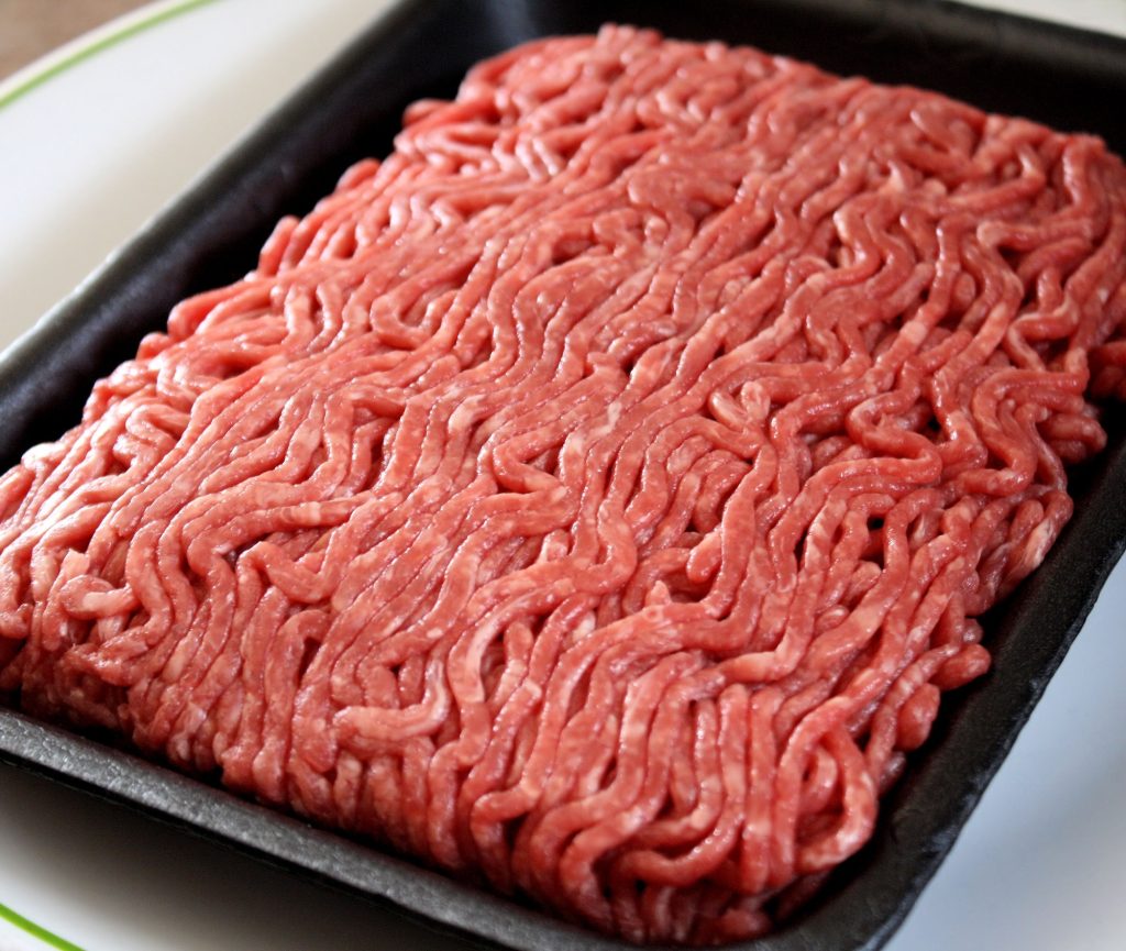 A pound of raw ground beef on a black styrofoam container.