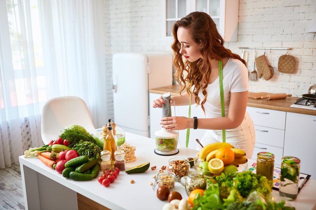 A woman in the kitchen surrounded buy ingredients, cooking.