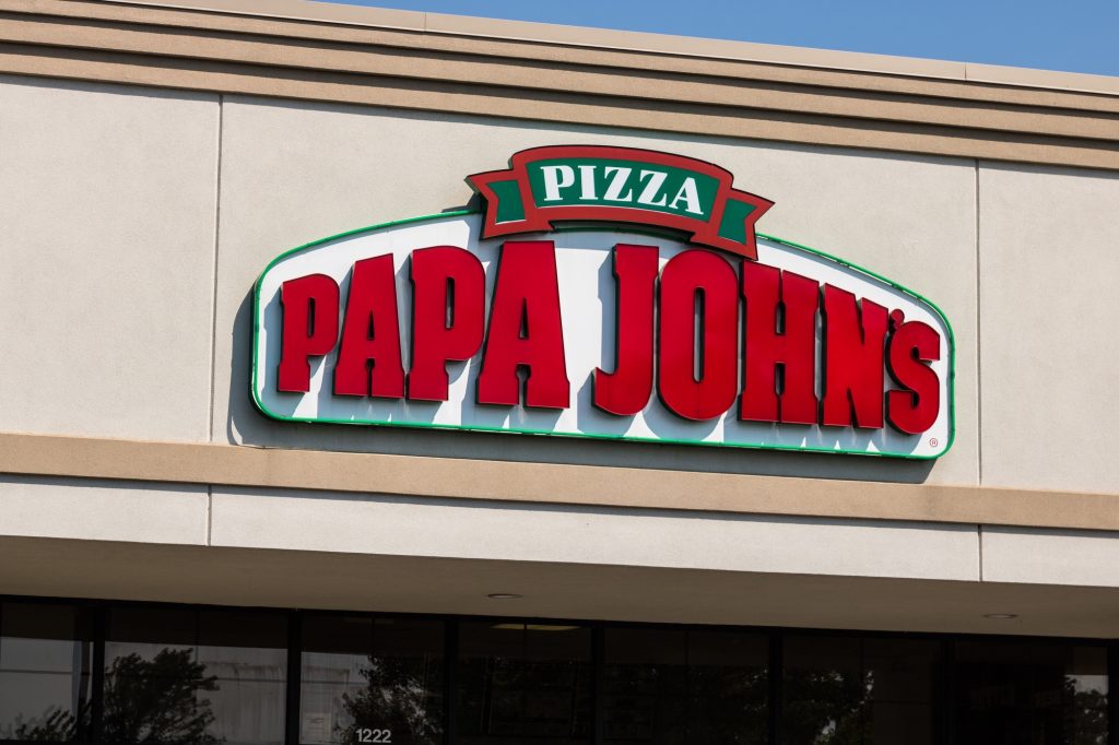 The papa johns pizza sign on the outside of a building.  