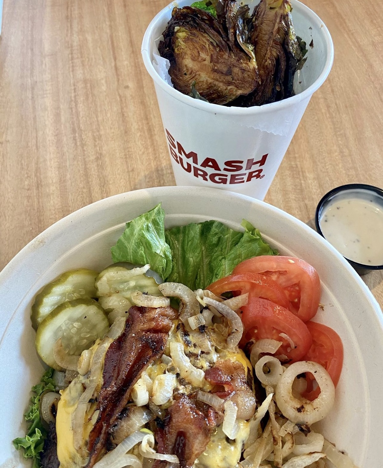 Smash burger bowl, no bun with veggies and lettuce, a side of fried Brussels sprouts with a side of ranch dressing for dipping.
