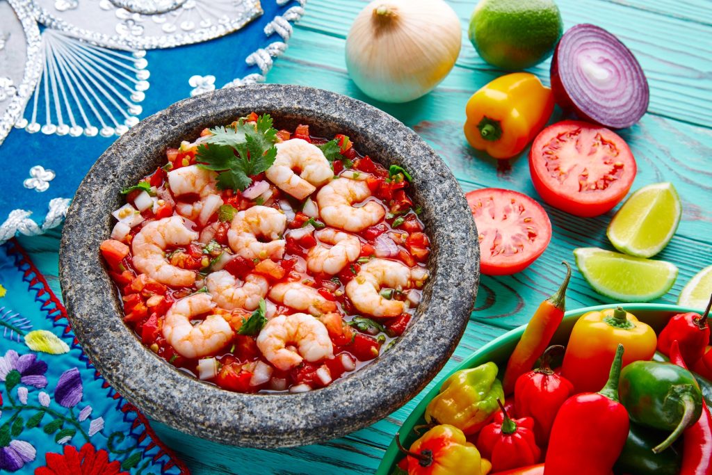 Shrimp ceveche in s stone bowl with all the fixings surrounding the bowl.