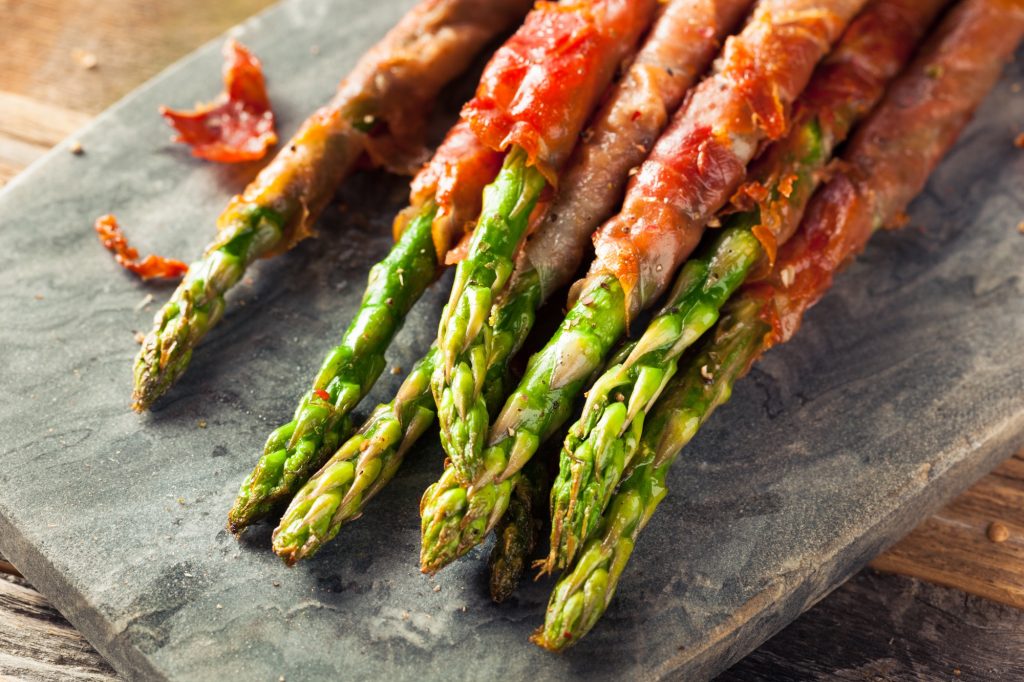 Proscuitto wrapped asparagus spears that appear to be roasted.