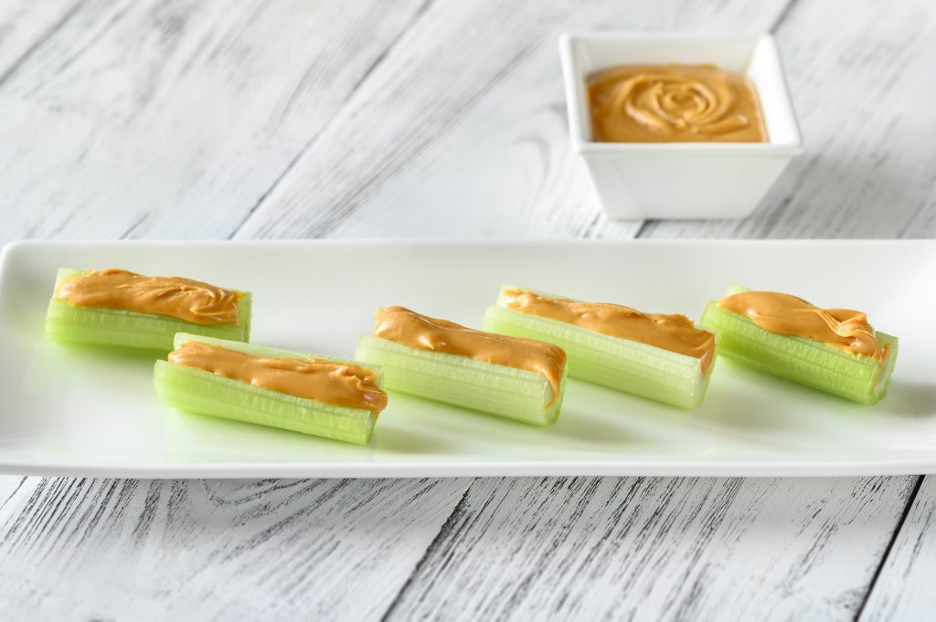 Celery sticks stuffed with peanut butter, on a white plate.