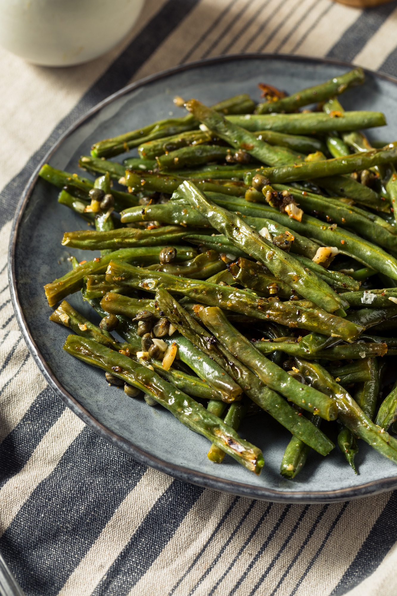 Seasoned cooked green beans in a blue bowl, sitting on a blue and white striped napkin.