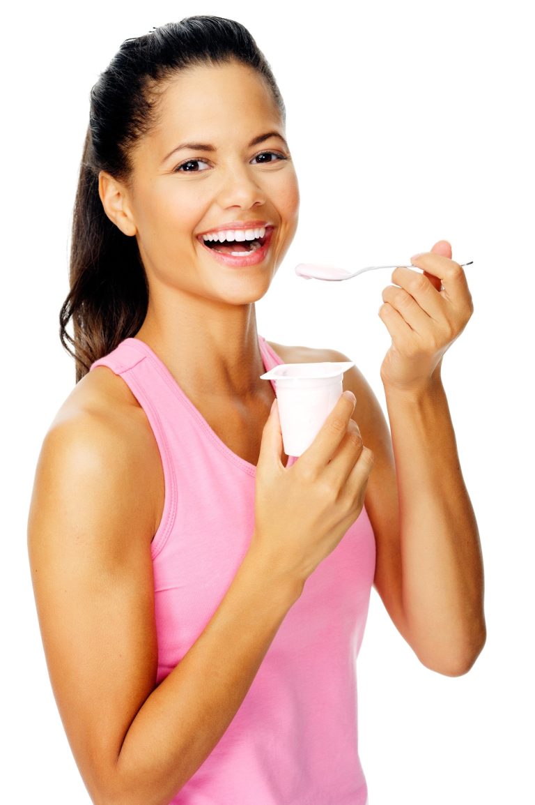 Woman smiling and eating yogurt.
