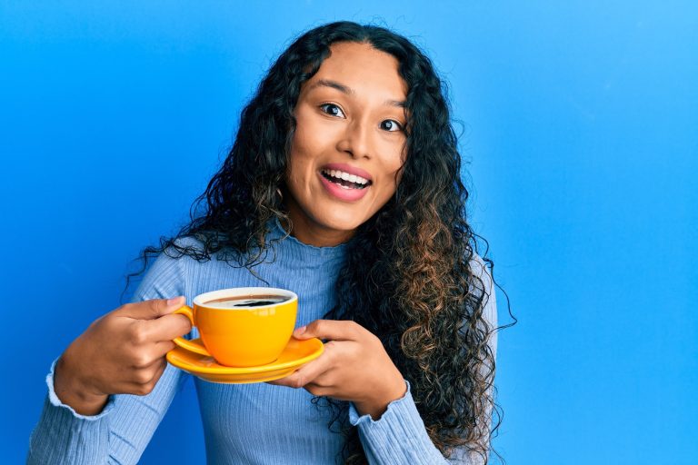 Brunette long hair woman drinking a cup of coffee, looks happy.