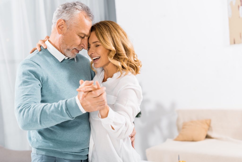 A middle age man and woman dancing closely, eyes closed.