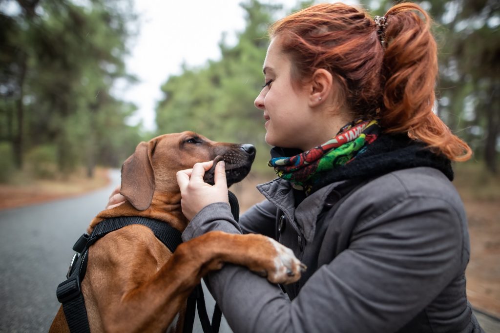 A woman and her dog outside hugging.