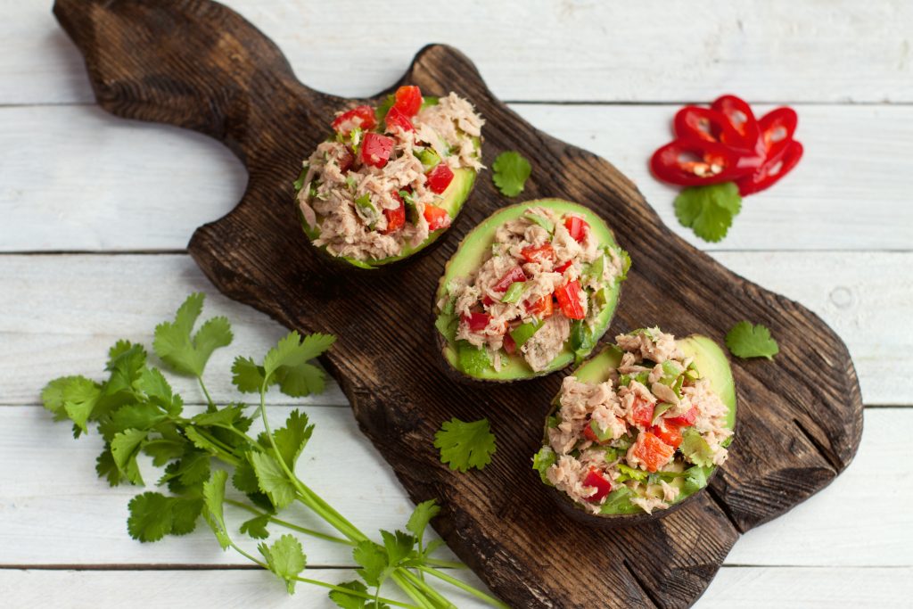Avocado halves stuffed with tuna salad and topped with tomatoes.