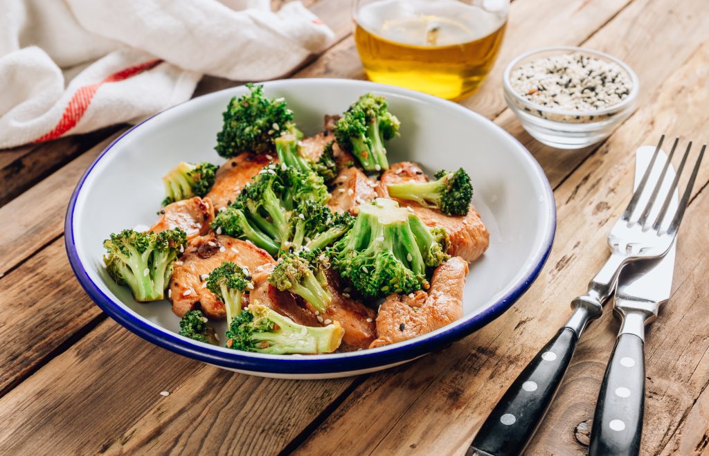 Chicken and broccoli in a white and blue-rimmed bowl. 