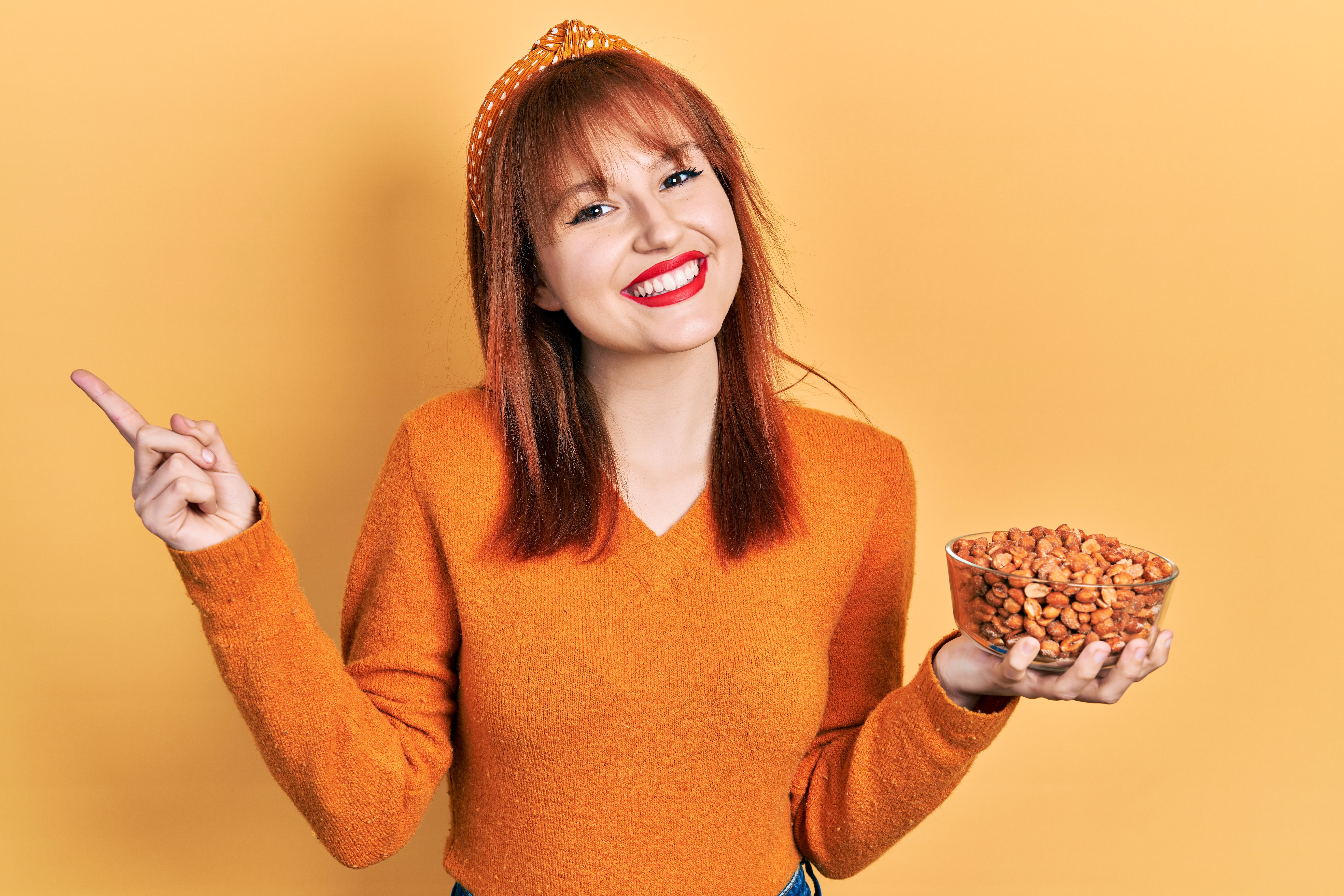 Smiling Woman holding nuts in one hand, pointing with the other.
