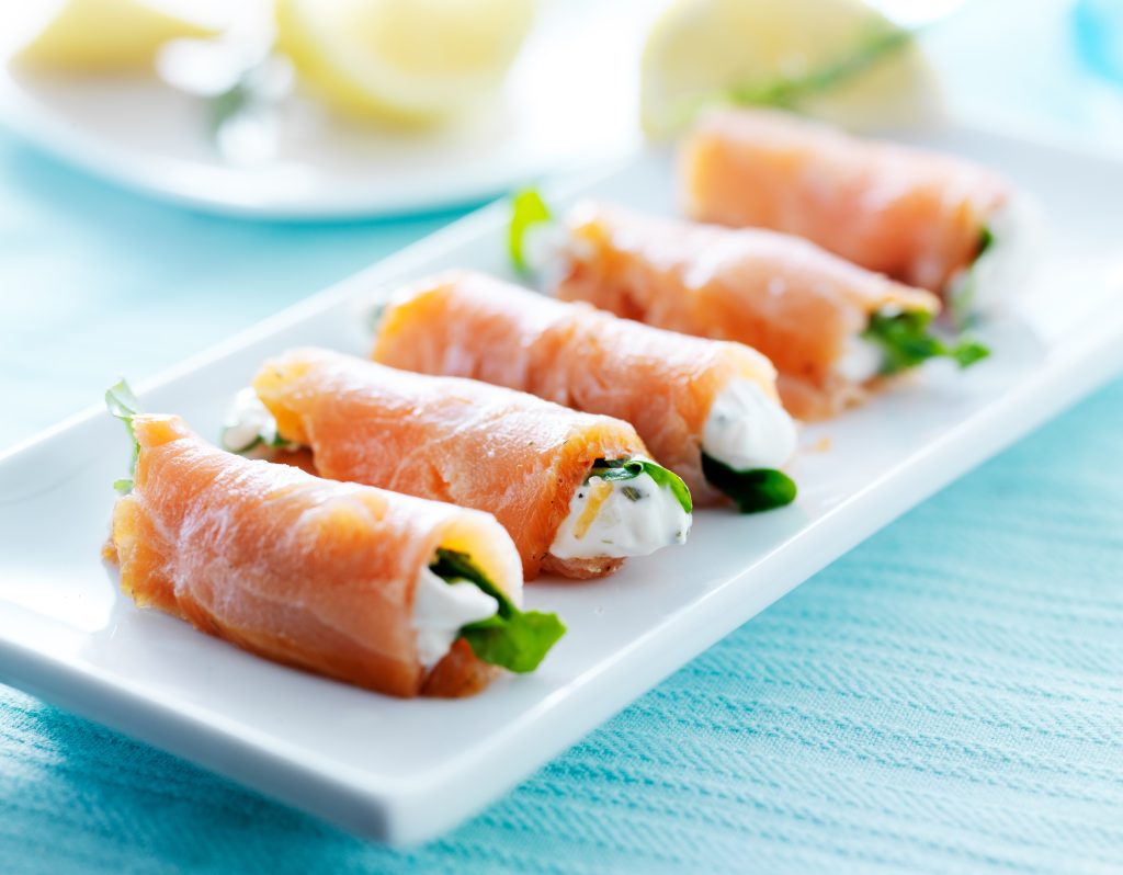 Salmon and cream cheese roll-ups on a white plate.