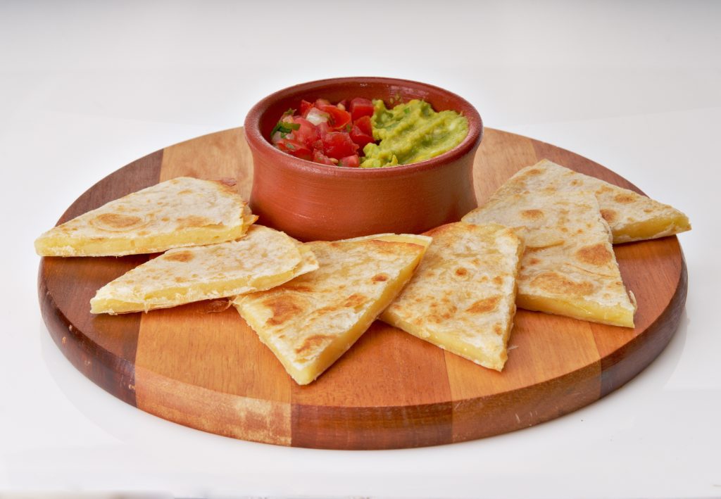 Cheese quesadillas on a wood board. A bowl of guacamole and pico.