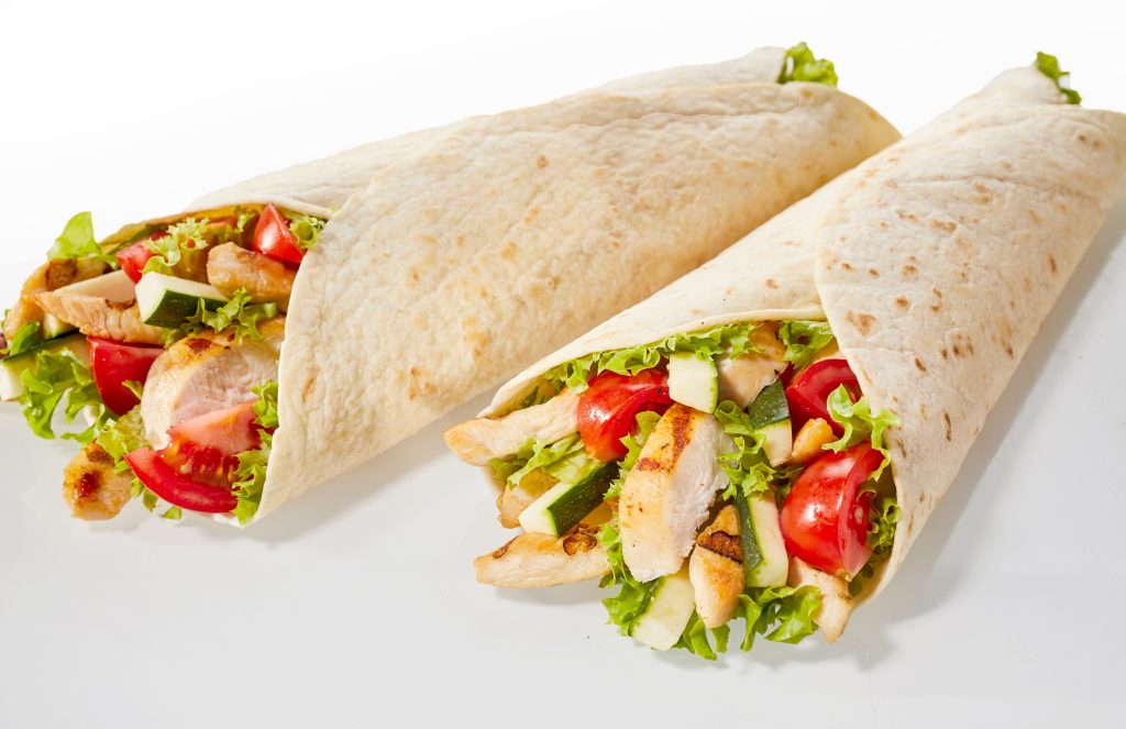 Two grilled Chicken Salad  Wraps with lettuce and tomatoes.
