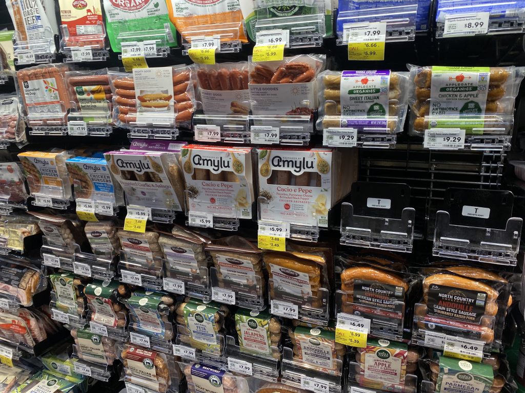 Packages of hot dogs and sausages in the cooler at the grocery.