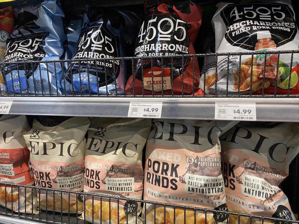 Bags of pork rinds on the shelf at the grocery.