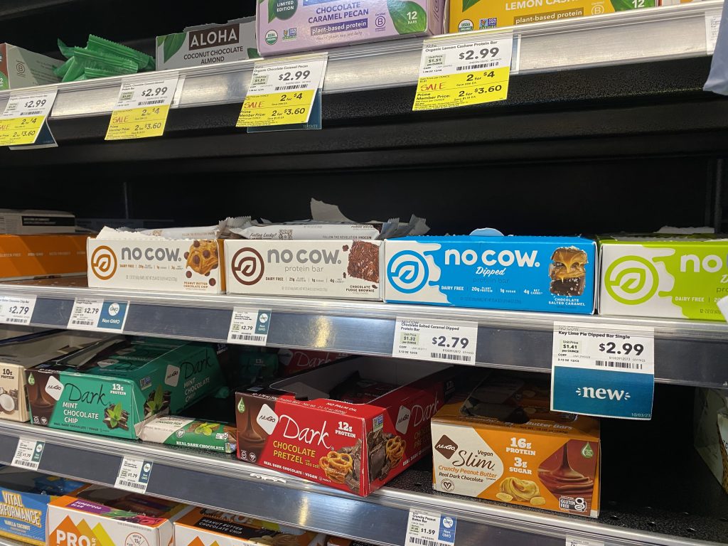 A variety of brands of protein bars on grocery shelf.