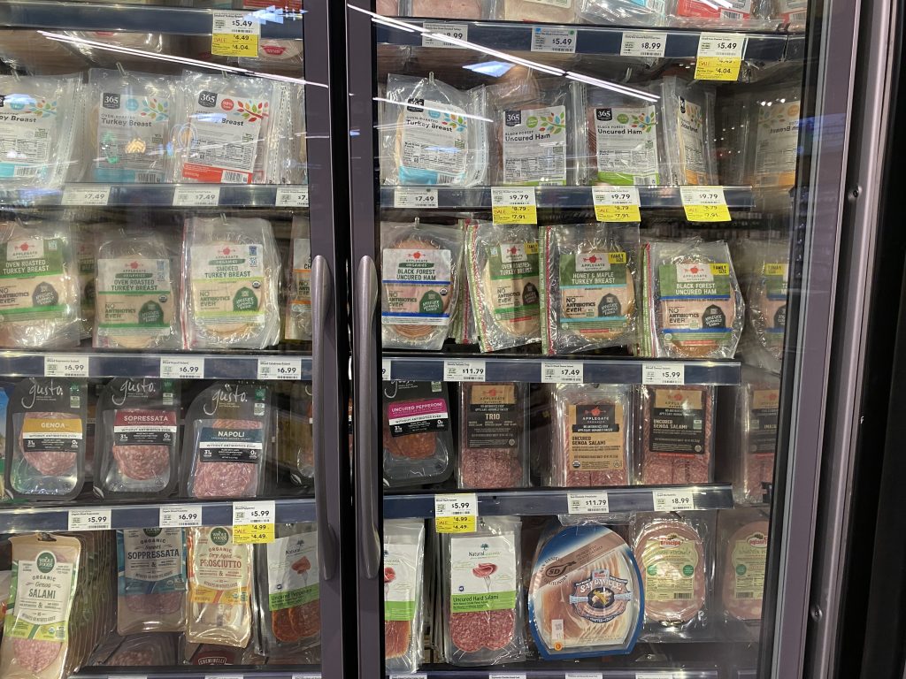 Packages of deli meats in the cooler at the grocery.