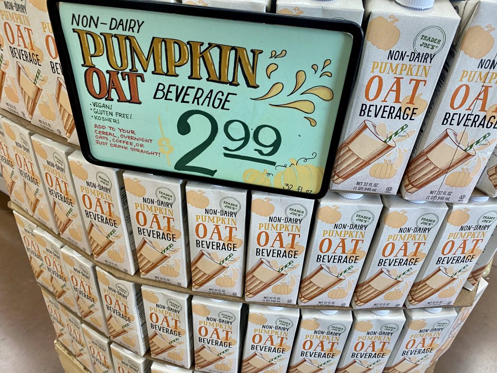 Boxes of pumpkin oat non dairy beverage on shelf at grocery.