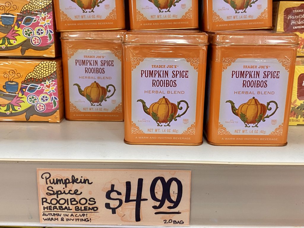 Tin cans of pumpkin spice herbal tea on grocery shelf.