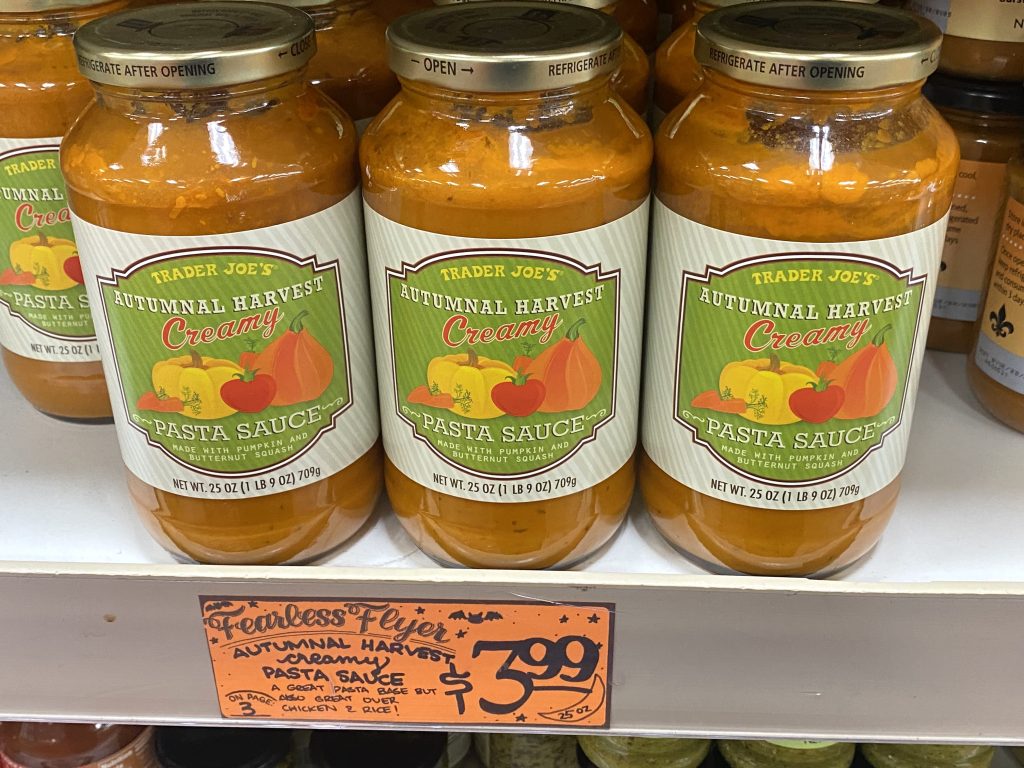 Jars of pumpkin marinara sauce on grocery shelf.