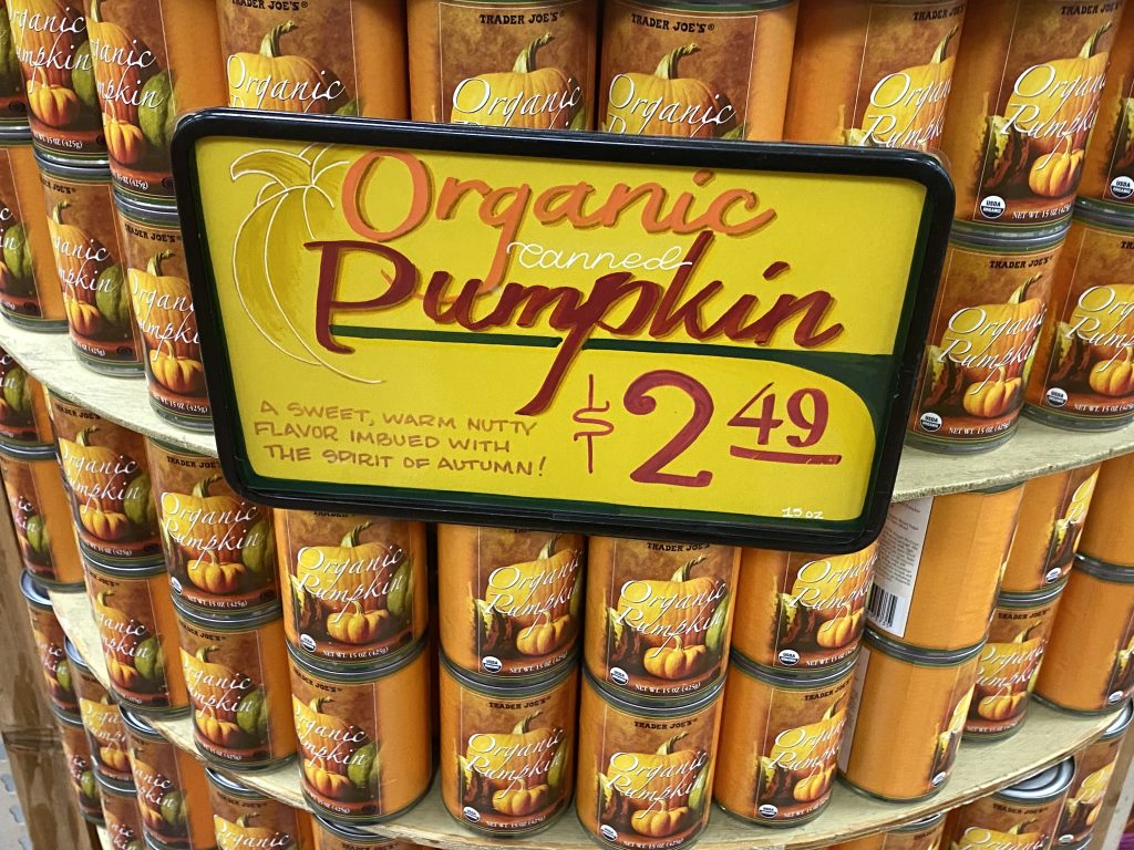 Cans of organic pumpkin on shelf at grocery.