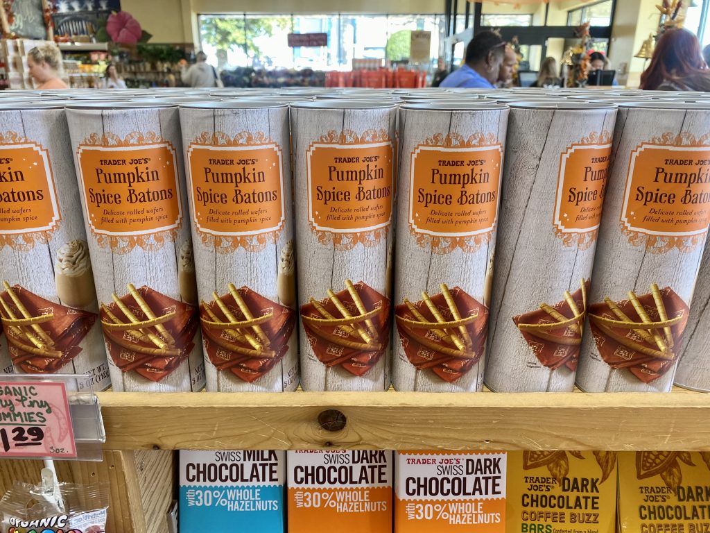 Canisters of pumpkin spice baton cookies on shelf at grocery.