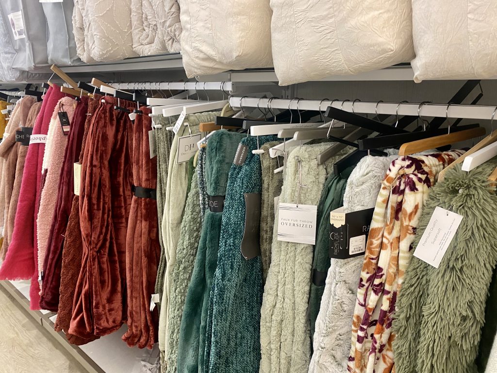 A store isle filled with blankets on hangers.