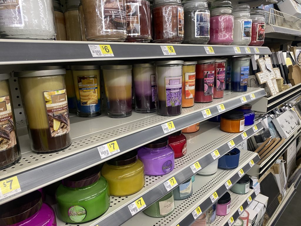 Multiple Jars of candles on store shelf.