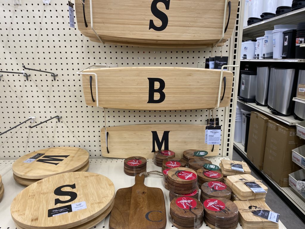 Decorative monogrammed wood cutting boards on shelf at store.