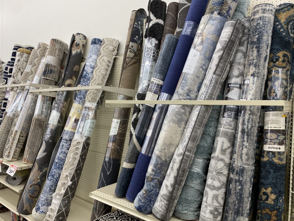 Rolled up area rugs leaned against wall, for sale at store.