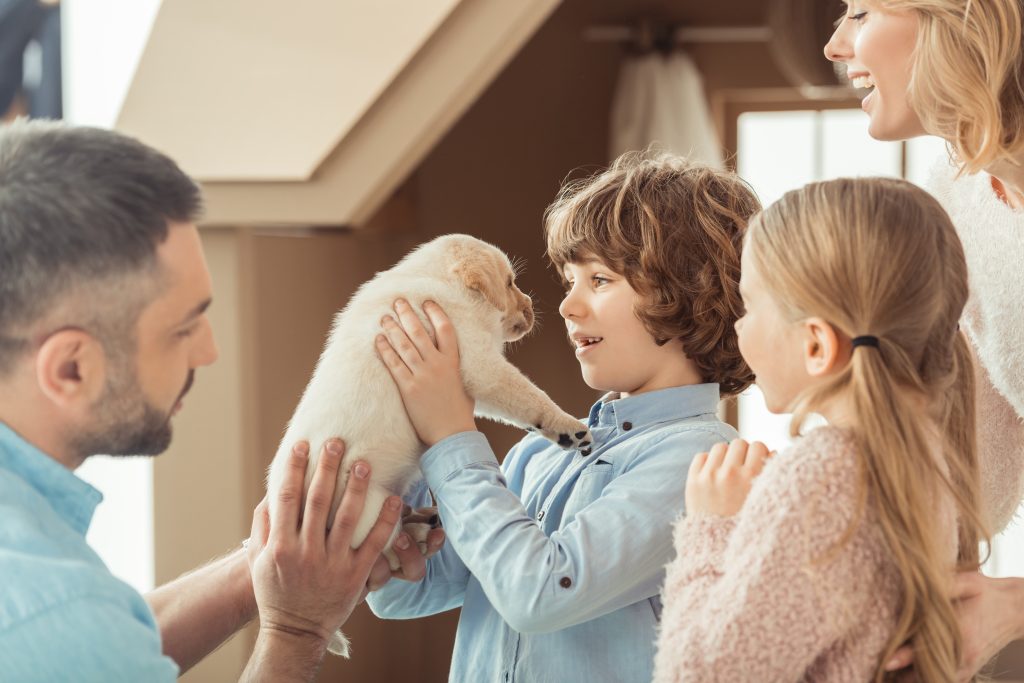 A family, a man, woman, little girl and boy holding a puppy.