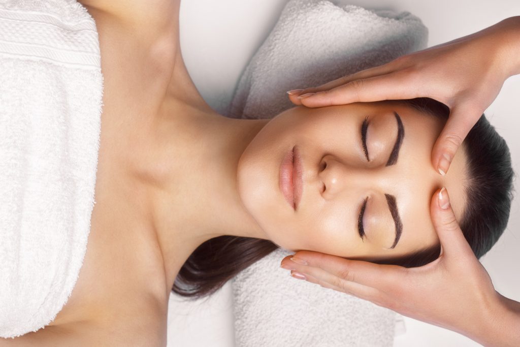 A woman at the spa laying flat getting a facial.