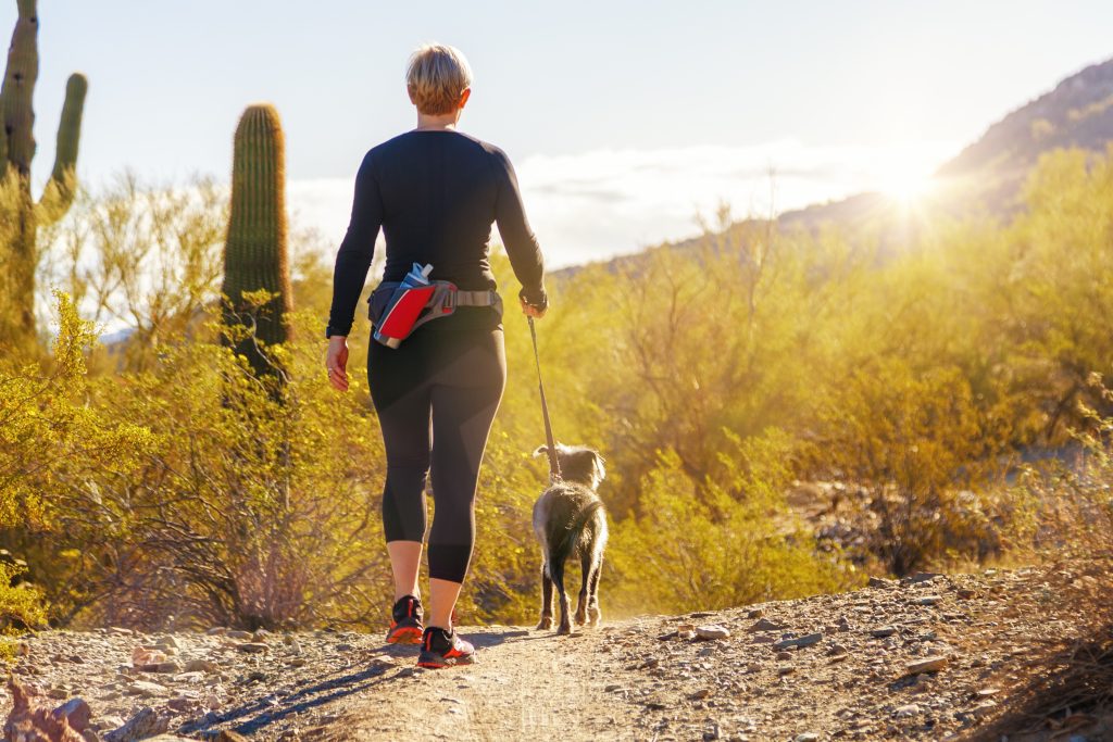 a woman hiking with a dog.