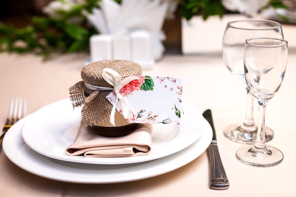 A table setting with a jar party favor on the plate.