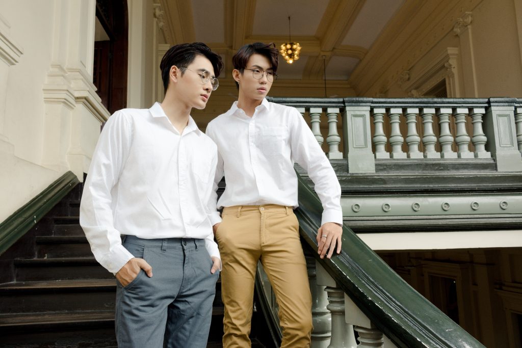 two men dressed in chinos and button down shirts staring into distance.