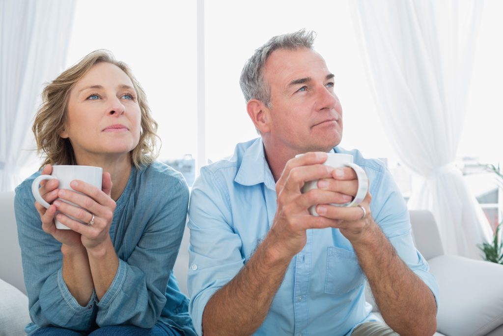 man and woman drinking coffee, staring in the distance, thinking.
