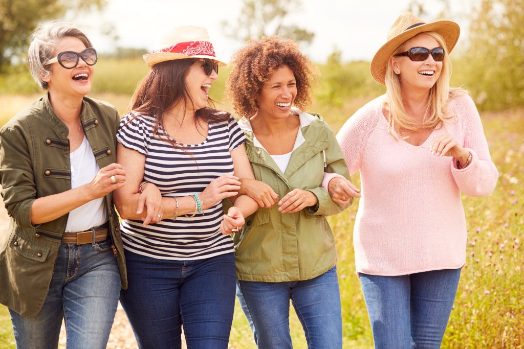 Happy group of female friends linking arms and walking.