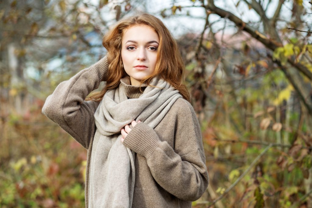 a woman wearing a beige cashmere sweater and scarf.